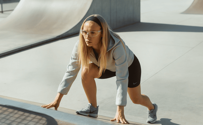 Mujer joven usando ropa deportiva, realizando actividad física luciendo concentrada, usando lentes para protección visual adecuados para un mejor rendimiento deportivo.